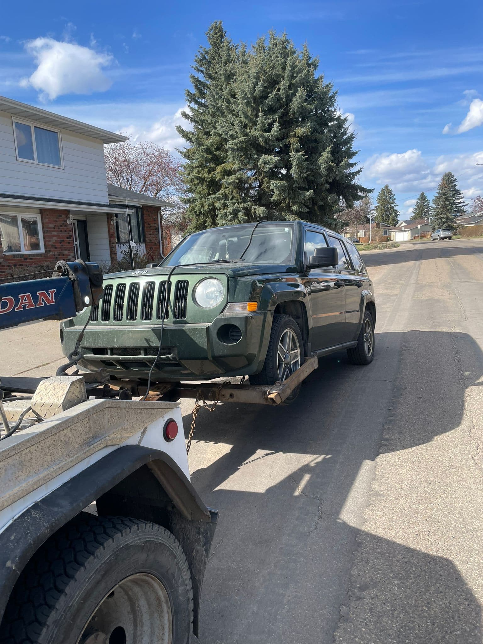 Damaged green Jeep Patriot loaded by an Edmonton cash-for-cars buyer